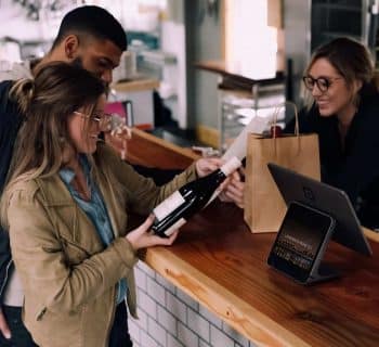 woman holding wine bottle beside man in front of woman smiling