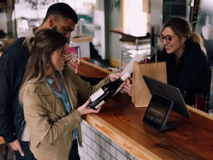 woman holding wine bottle beside man in front of woman smiling