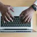 person's hand on MacBook near iPhone flat lay photography